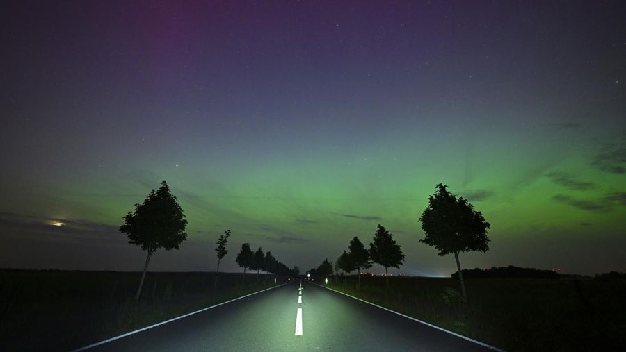 In this image taken with a long exposure, cars pass by as people look at the night sky towards the northern lights, or Aurora Borealis, on Friday, May 10, 2024, in Estacada, Ore. The National Oceanic and Atmospheric Administration issued a rare severe geomagnetic storm warning when a solar outburst reached Earth on Friday afternoon, hours sooner than anticipated. The effects were due to last through the weekend and possibly into next week. (AP Photo/Jenny Kane)
