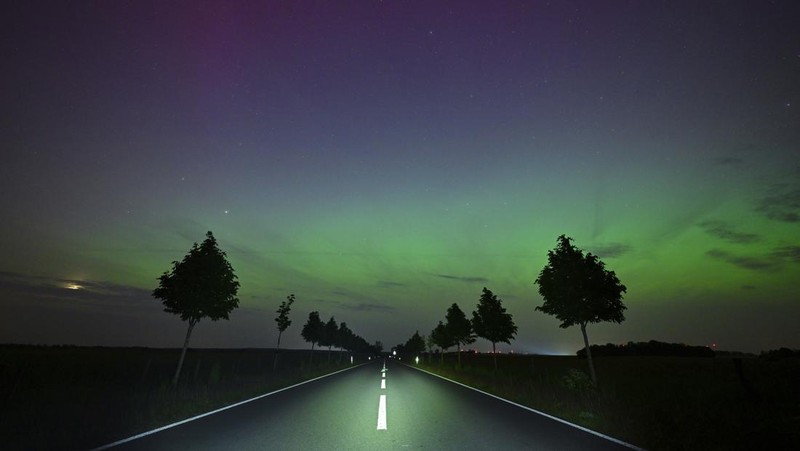 In this image taken with a long exposure, cars pass by as people look at the night sky towards the northern lights, or Aurora Borealis, on Friday, May 10, 2024, in Estacada, Ore. The National Oceanic and Atmospheric Administration issued a rare severe geomagnetic storm warning when a solar outburst reached Earth on Friday afternoon, hours sooner than anticipated. The effects were due to last through the weekend and possibly into next week. (AP Photo/Jenny Kane)