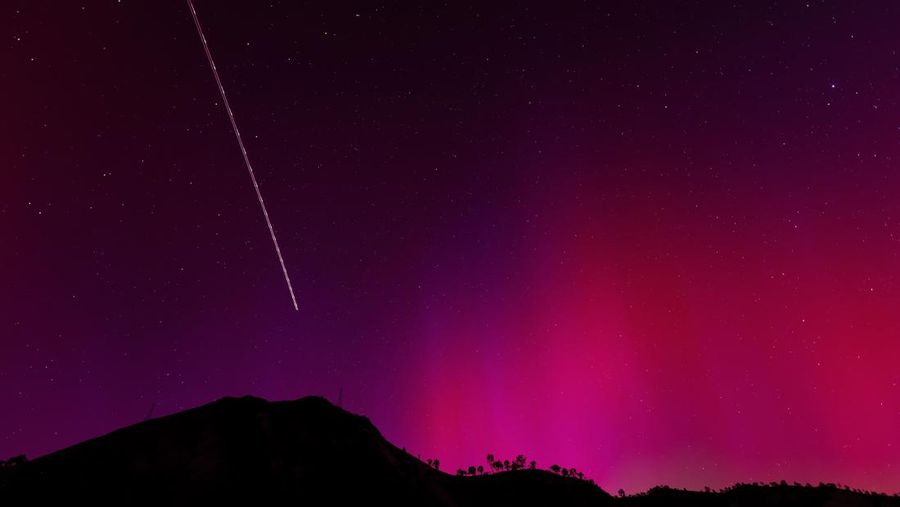 In this image taken with a long exposure, cars pass by as people look at the night sky towards the northern lights, or Aurora Borealis, on Friday, May 10, 2024, in Estacada, Ore. The National Oceanic and Atmospheric Administration issued a rare severe geomagnetic storm warning when a solar outburst reached Earth on Friday afternoon, hours sooner than anticipated. The effects were due to last through the weekend and possibly into next week. (AP Photo/Jenny Kane)