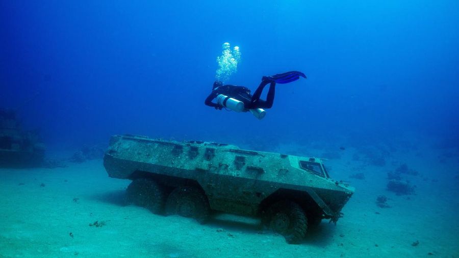 Seorang penyelam berenang di samping kendaraan militer yang tenggelam di Museum Militer Bawah Air di Aqaba, Yordania, 7 Mei 2024. (REUTERS/Stelios Misinas)