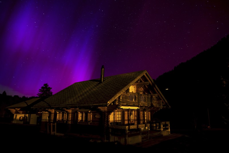 In this image taken with a long exposure, cars pass by as people look at the night sky towards the northern lights, or Aurora Borealis, on Friday, May 10, 2024, in Estacada, Ore. The National Oceanic and Atmospheric Administration issued a rare severe geomagnetic storm warning when a solar outburst reached Earth on Friday afternoon, hours sooner than anticipated. The effects were due to last through the weekend and possibly into next week. (AP Photo/Jenny Kane)