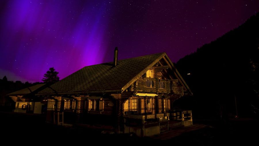 The Northern Lights, or Aurora Borealis, illuminate the night sky over the mountains in Le Col des Mosses pass, Ormont-Dessous, Switzerland, during the early hours of Saturday, May 11, 2024. (Jean-Christophe Bott/Keystone via AP)