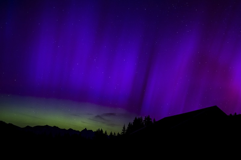 In this image taken with a long exposure, cars pass by as people look at the night sky towards the northern lights, or Aurora Borealis, on Friday, May 10, 2024, in Estacada, Ore. The National Oceanic and Atmospheric Administration issued a rare severe geomagnetic storm warning when a solar outburst reached Earth on Friday afternoon, hours sooner than anticipated. The effects were due to last through the weekend and possibly into next week. (AP Photo/Jenny Kane)