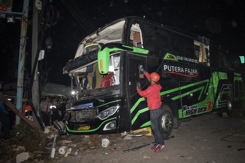 Officers check the debris and belongings of passengers after a bus crash that killed 11 people, according to local police, in Subang, West Java, on May 11, 2024. (Photo by Timur MATAHARI / AFP)