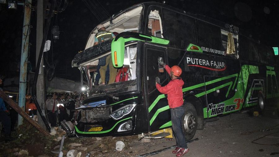 Officers check the damaged bus after a crash that killed 11 people, according to local police, in Subang, West Java, on May 11, 2024. (Photo by Timur MATAHARI / AFP)