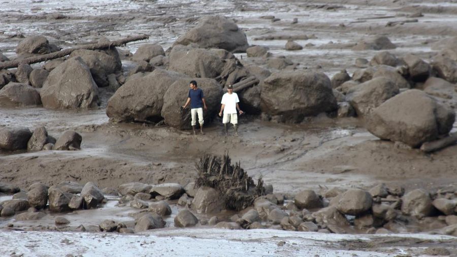 People inspect an area affected by flash flood in Agam, West Sumatra, Indonesia, Sunday, May 12, 2024. Heavy rains and torrents of cold lava and mud rushing down a volcano on Indonesia’s Sumatra island have triggered flash floods that killed more than a dozen of people and injured several others, officials said Sunday.  (AP Photo/Ali Nayaka)