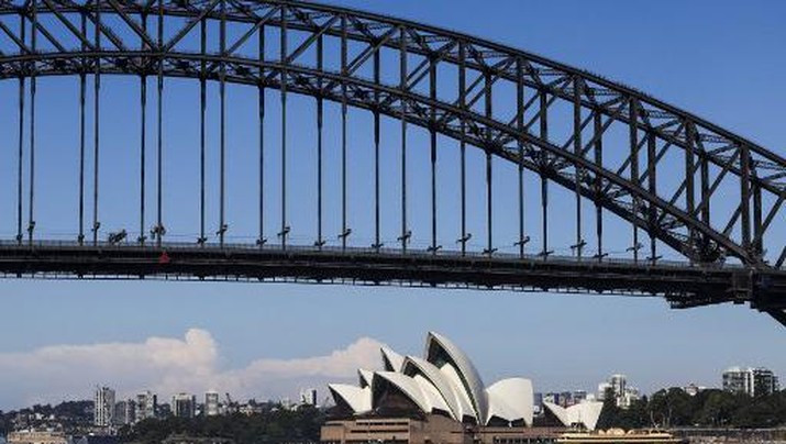 A ferry passes the Sydney Opera House as flags atop the Sydney Harbour Bridge fly at half-mast on April 15, 2024, as a mark of respect for the victims of the Westfield Bondi Junction shopping mall attack. A 40-year-old knifeman with mental illness roamed the packed shopping centre on April 13, killing six people and seriously wounding a dozen others. (Photo by DAVID GRAY / AFP)