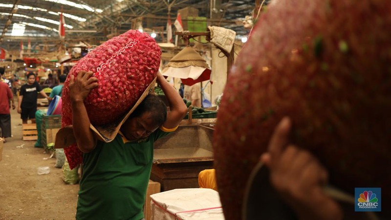 Pekerja membersihkan bawang merah yang baru tiba dari Brebes, di Pasar Induk, Kramat Jati, Jakarta Senin (13/5/2024). (CNBC Indonesia/Tri Susilo)
