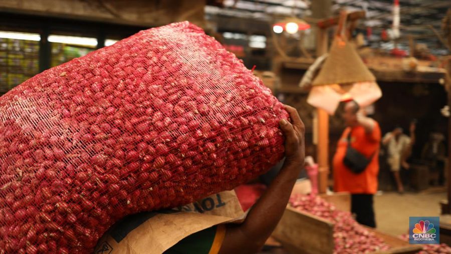 Pekerja membersihkan bawang merah yang baru tiba dari Brebes, di Pasar Induk, Kramat Jati, Jakarta Senin (13/5/2024). (CNBC Indonesia/Tri Susilo)