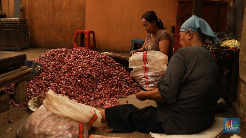 Pekerja membersihkan bawang merah yang baru tiba dari Brebes, di Pasar Induk, Kramat Jati, Jakarta Senin (13/5/2024). (CNBC Indonesia/Tri Susilo)