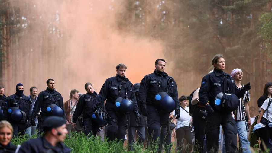 Petugas polisi berjalan dalam antrean, saat para aktivis memprotes perluasan Tesla Gigafactory di Gruenheide dekat Berlin, Jerman, 11 Mei 2024. (REUTERS/Christian Mang)