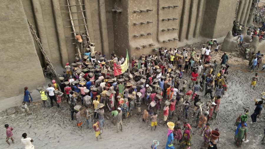Warga Mali mengambil bagian dalam pekerjaan plesteran ulang tahunan bangunan bata lumpur terbesar di dunia, Masjid Agung Djenne, Mali, Minggu, 12 Mei 2024. Bangunan tersebut masuk dalam daftar Warisan Dunia dalam Bahaya UNESCO sejak 2016. Masjid dan kota sekitarnya terancam oleh konflik. Masjid Djenne memerlukan lapisan lumpur baru setiap tahun sebelum dimulainya musim hujan di bulan Juni. (AP Photo/Moustapha Diallo)
