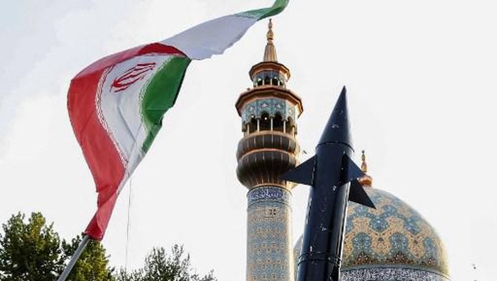 Iranians lift up a flag and the mock up of a missile during a celebration following Iran's missiles and drones attack on Israel, on April 15 2024, at Palestine square in central Tehran. Iran launched the attack on April 14, its first ever to directly target Israeli territory, in retaliation for a deadly air strike widely blamed on Israel that destroyed Tehran's consular building in Syria's capital early this month. (Photo by ATTA KENARE / AFP)