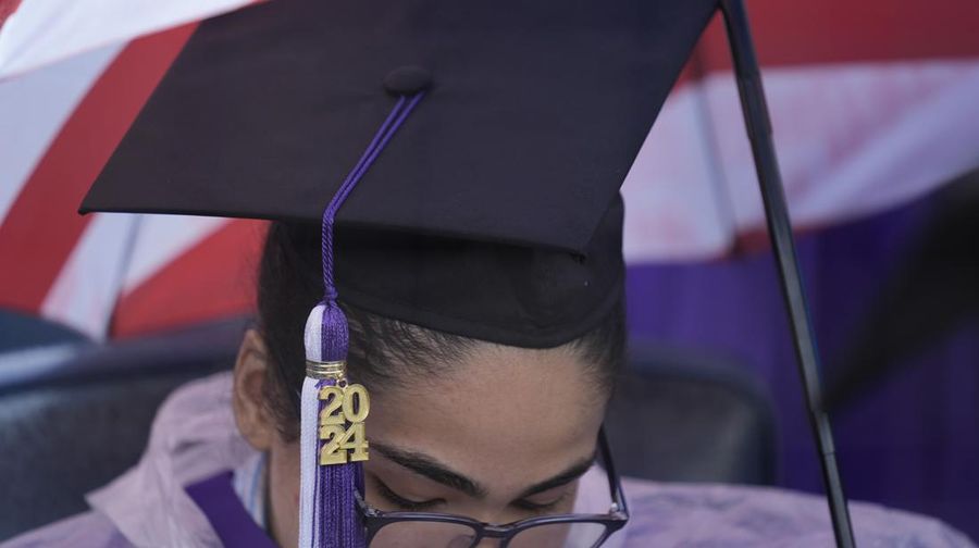 A New York University graduate sits in the rain before the start of the commencement ceremony at Yankee Stadium in New York, Wednesday, May 15, 2024. (AP Photo/Seth Wenig)