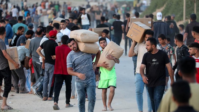 Warga Palestina menaiki truk untuk mengambil bantuan yang dikirim ke Gaza melalui dermaga buatan AS, di tengah konflik yang sedang berlangsung antara Israel dan kelompok Islam Palestina Hamas, terlihat dari pusat Jalur Gaza, 18 Mei 2024. (REUTERS/Ramadan Abed)