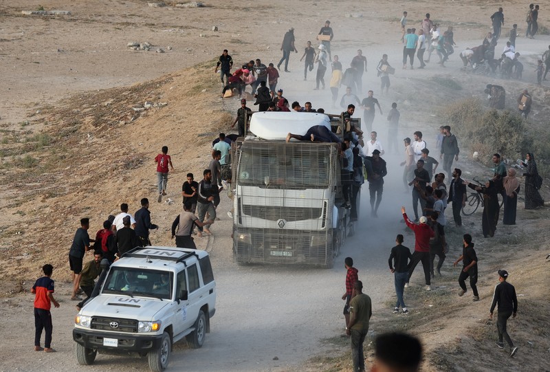 Warga Palestina menaiki truk untuk mengambil bantuan yang dikirim ke Gaza melalui dermaga buatan AS, di tengah konflik yang sedang berlangsung antara Israel dan kelompok Islam Palestina Hamas, terlihat dari pusat Jalur Gaza, 18 Mei 2024. Warga Palestina menaiki truk untuk mengambil bantuan yang dikirim ke Gaza melalui dermaga buatan AS, di tengah konflik yang sedang berlangsung antara Israel dan kelompok Islam Palestina Hamas, terlihat dari pusat Jalur Gaza, 18 Mei 2024. (REUTERS/Ramadan Abed)