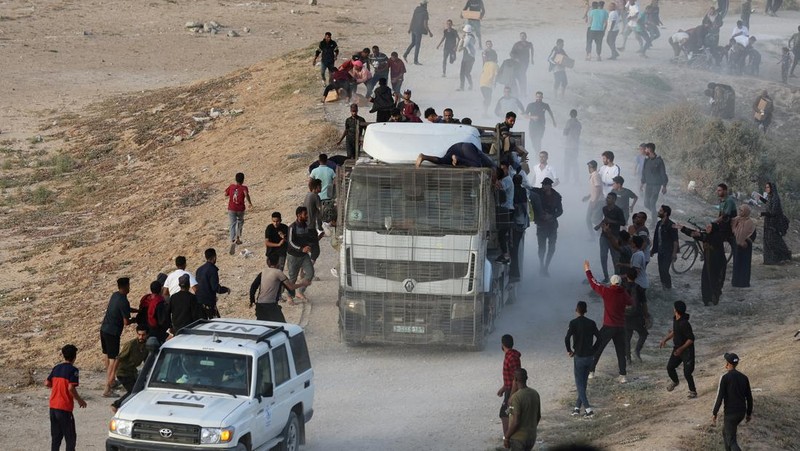 Warga Palestina menaiki truk untuk mengambil bantuan yang dikirim ke Gaza melalui dermaga buatan AS, di tengah konflik yang sedang berlangsung antara Israel dan kelompok Islam Palestina Hamas, terlihat dari pusat Jalur Gaza, 18 Mei 2024. (REUTERS/Ramadan Abed)