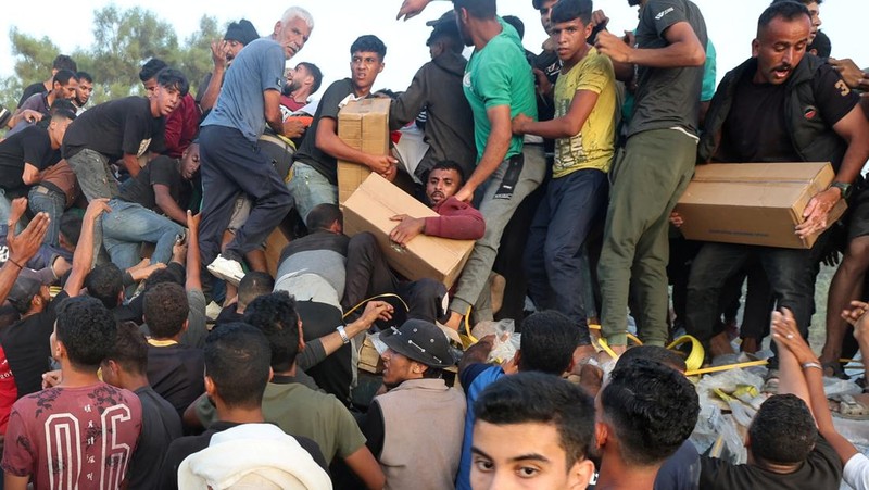 Warga Palestina menaiki truk untuk mengambil bantuan yang dikirim ke Gaza melalui dermaga buatan AS, di tengah konflik yang sedang berlangsung antara Israel dan kelompok Islam Palestina Hamas, terlihat dari pusat Jalur Gaza, 18 Mei 2024. (REUTERS/Ramadan Abed)