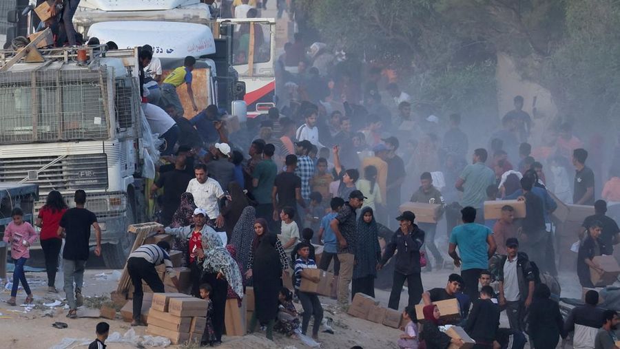 Warga Palestina menaiki truk untuk mengambil bantuan yang dikirim ke Gaza melalui dermaga buatan AS, di tengah konflik yang sedang berlangsung antara Israel dan kelompok Islam Palestina Hamas, terlihat dari pusat Jalur Gaza, 18 Mei 2024. (REUTERS/Ramadan Abed)