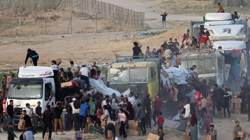 Warga Palestina menaiki truk untuk mengambil bantuan yang dikirim ke Gaza melalui dermaga buatan AS, di tengah konflik yang sedang berlangsung antara Israel dan kelompok Islam Palestina Hamas, terlihat dari pusat Jalur Gaza, 18 Mei 2024. (REUTERS/Ramadan Abed)