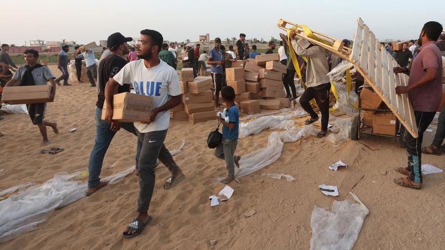 Warga Palestina menaiki truk untuk mengambil bantuan yang dikirim ke Gaza melalui dermaga buatan AS, di tengah konflik yang sedang berlangsung antara Israel dan kelompok Islam Palestina Hamas, terlihat dari pusat Jalur Gaza, 18 Mei 2024. (REUTERS/Ramadan Abed)
