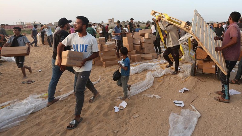 Warga Palestina menaiki truk untuk mengambil bantuan yang dikirim ke Gaza melalui dermaga buatan AS, di tengah konflik yang sedang berlangsung antara Israel dan kelompok Islam Palestina Hamas, terlihat dari pusat Jalur Gaza, 18 Mei 2024. (REUTERS/Ramadan Abed)