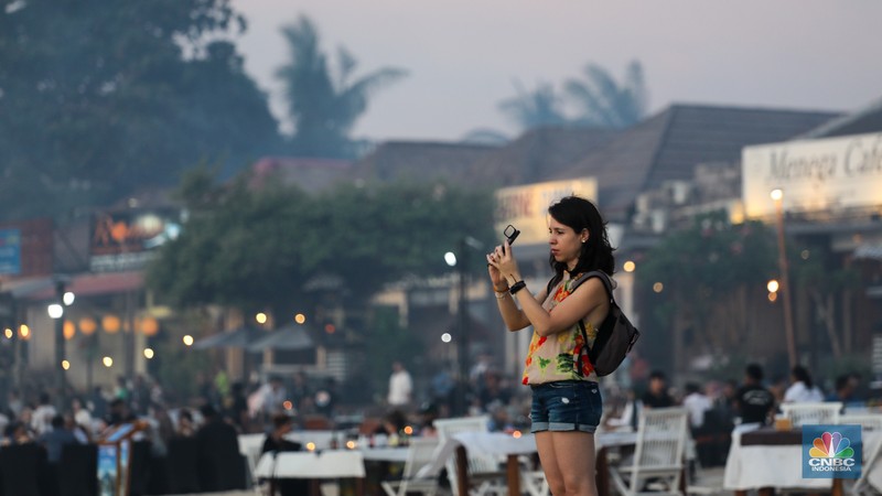 Wisatawan menikmati fenomena matahari tenggelam atau sunset di Pantai Muaya, Jimbaran, Bali, Selasa (21/5/2024). (CNBC Indonesia/Faisal Rahman)