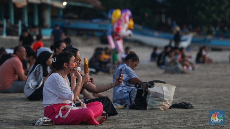 Wisatawan menikmati fenomena matahari tenggelam atau sunset di Pantai Muaya, Jimbaran, Bali, Selasa (21/5/2024). (CNBC Indonesia/Faisal Rahman)