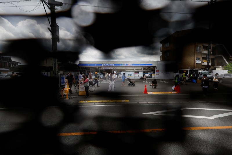 Para pekerja mendirikan barikade di dekat toko serba ada Lawson, tempat berfoto populer yang membingkai pemandangan indah dengan latar belakang Gunung Fuji di Fujikawaguchiko, Prefektur Yamanashi, Jepang tengah, Selasa (30/4/2024). (REUTERS/Kim Kyung-Hoon)