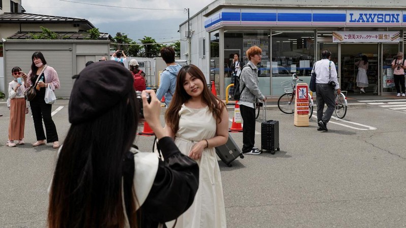 Para pekerja mendirikan barikade di dekat toko serba ada Lawson, tempat berfoto populer yang membingkai pemandangan indah dengan latar belakang Gunung Fuji di Fujikawaguchiko, Prefektur Yamanashi, Jepang tengah, Selasa (30/4/2024). (REUTERS/Kim Kyung-Hoon)