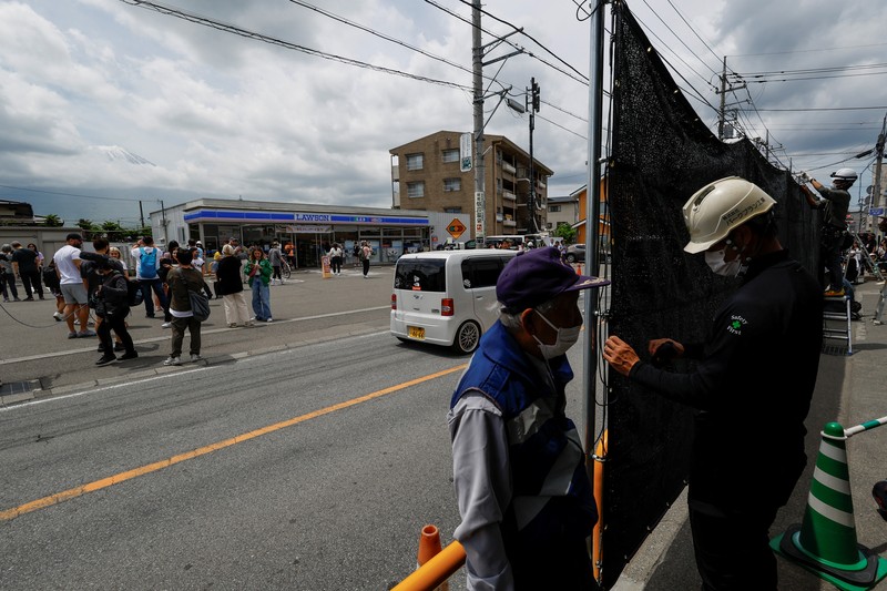 Para pekerja mendirikan barikade di dekat toko serba ada Lawson, tempat berfoto populer yang membingkai pemandangan indah dengan latar belakang Gunung Fuji di Fujikawaguchiko, Prefektur Yamanashi, Jepang tengah, Selasa (30/4/2024). (REUTERS/Kim Kyung-Hoon)