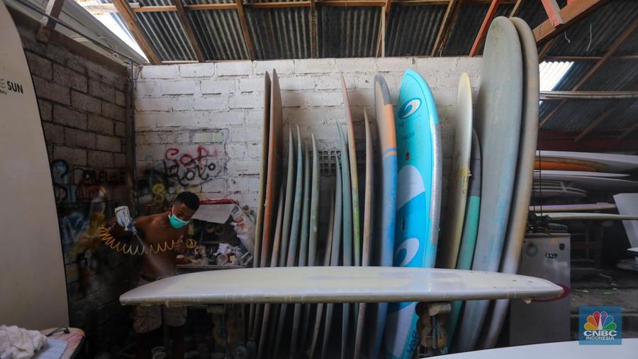 Pekerja menyelesaikan proses pembuatan papan selancar (surfing) di Workshop Rezeki Selancar di kawasan Kuta, Badung, Bali, Rabu (22/5/2024). (CNBC Indonesia/Faisal Rahman)