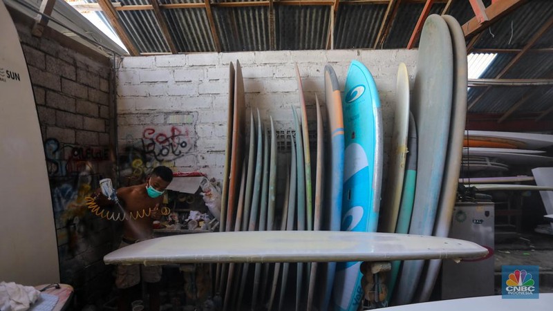 Pekerja menyelesaikan proses pembuatan papan selancar (surfing) di Workshop Rezeki Selancar di kawasan Kuta, Badung, Bali, Rabu (22/5/2024). (CNBC Indonesia/Faisal Rahman)