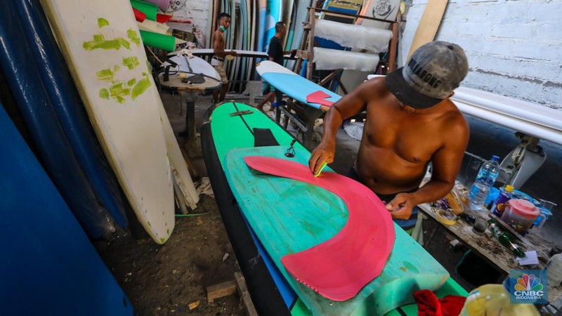Pekerja menyelesaikan proses pembuatan papan selancar (surfing) di Workshop Rezeki Selancar di kawasan Kuta, Badung, Bali, Rabu (22/5/2024). (CNBC Indonesia/Faisal Rahman)