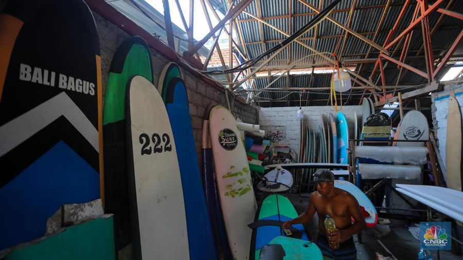 Pekerja menyelesaikan proses pembuatan papan selancar (surfing) di Workshop Rezeki Selancar di kawasan Kuta, Badung, Bali, Rabu (22/5/2024). (CNBC Indonesia/Faisal Rahman)
