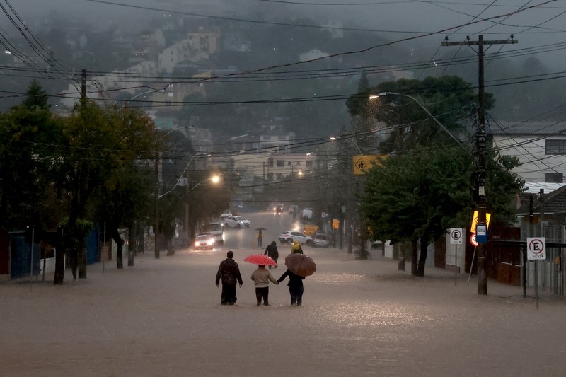Orang-orang berjalan di daerah banjir di lingkungan Cavalhada setelah hujan lebat di Porto Alegre, Brasil 23 Mei 2024. (REUTERS/Diego Vara)