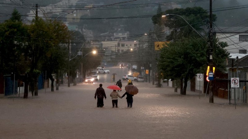 Orang-orang berjalan di daerah banjir di lingkungan Cavalhada setelah hujan lebat di Porto Alegre, Brasil 23 Mei 2024. (REUTERS/Diego Vara)