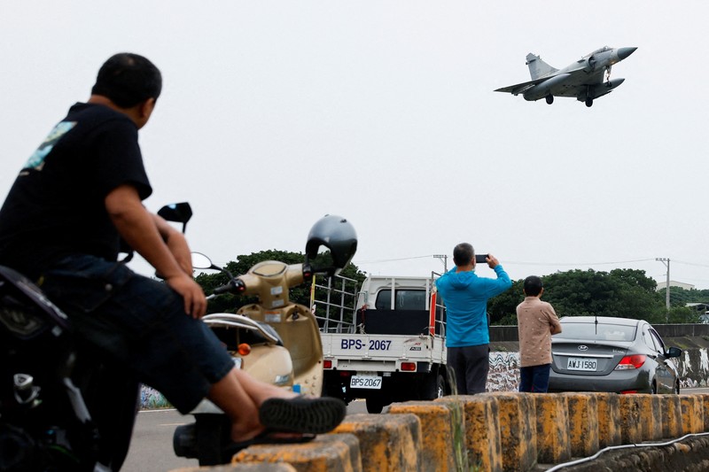 Seorang pelaut Taiwan di atas kapal Angkatan Laut melihat ke arah kapal perang Tiongkok saat bernavigasi di perairan lepas pantai barat Taiwan. (via REUTERS/TAIWAN DEFENCE MINISTRY)