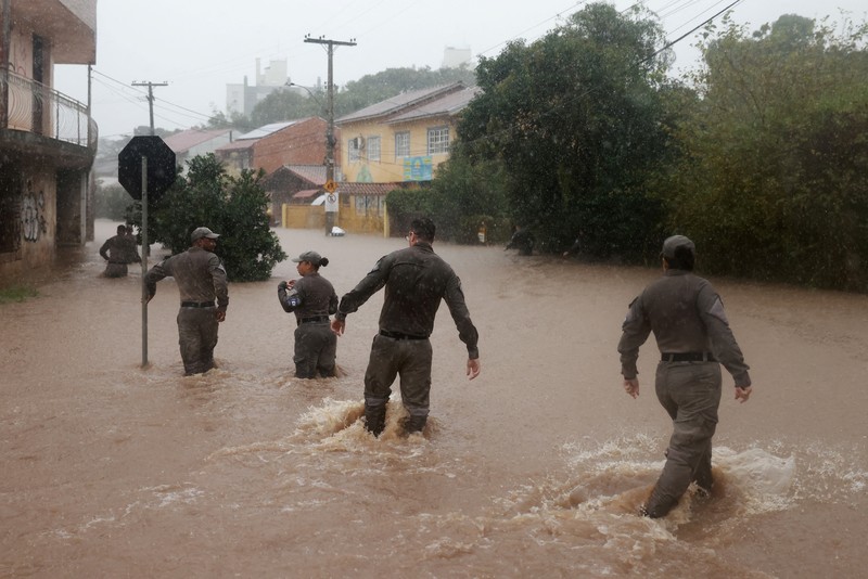 Orang-orang berjalan di daerah banjir di lingkungan Cavalhada setelah hujan lebat di Porto Alegre, Brasil 23 Mei 2024. (REUTERS/Diego Vara)