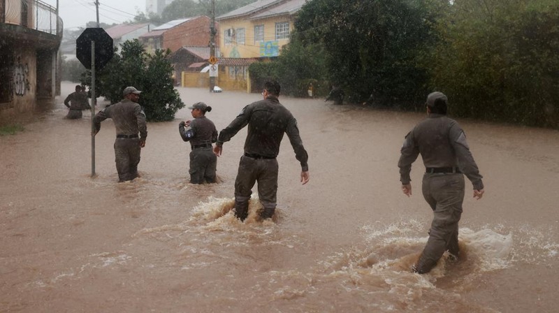 Orang-orang berjalan di daerah banjir di lingkungan Cavalhada setelah hujan lebat di Porto Alegre, Brasil 23 Mei 2024. (REUTERS/Diego Vara)