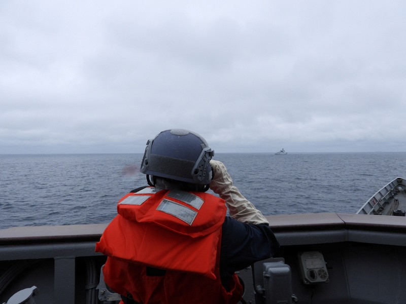 Seorang pelaut Taiwan di atas kapal Angkatan Laut melihat ke arah kapal perang Tiongkok saat bernavigasi di perairan lepas pantai barat Taiwan. (via REUTERS/TAIWAN DEFENCE MINISTRY)