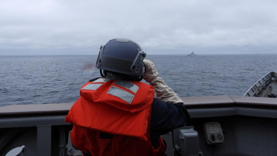 Seorang pelaut Taiwan di atas kapal Angkatan Laut melihat ke arah kapal perang Tiongkok saat bernavigasi di perairan lepas pantai barat Taiwan. (via REUTERS/TAIWAN DEFENCE MINISTRY)