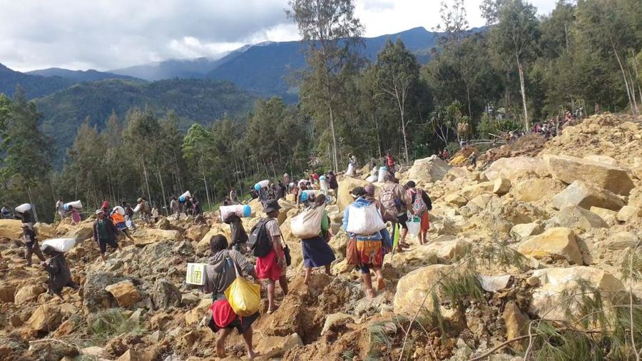 Orang-orang membawa tas pasca bencana tanah longsor di Provinsi Enga, Papua Nugini, 24 Mei 2024. Tanah longsor melanda Desa Kaokalam di Provinsi Enga, sekitar 600 kilometer barat laut Port Moresby, sekitar pukul 03.00. (via REUTERS/Andrew Ruing)