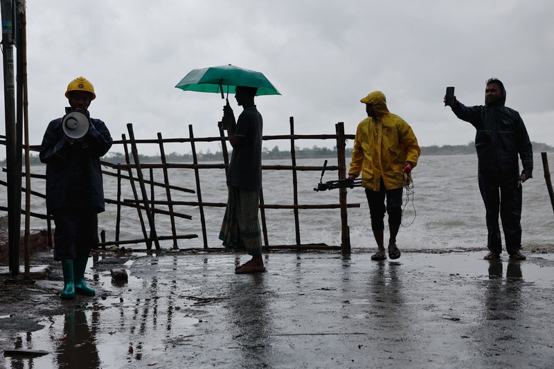 Seorang pria menyelamatkan gerobak dan material lainnya saat air mengalir ke pantai Kuakata di pesisir Teluk Benggala akibat mendekatnya Topan Remal di Barisal, Bangladesh, Minggu, 26 Mei 2024. (AP Photo/Abdul Goni)