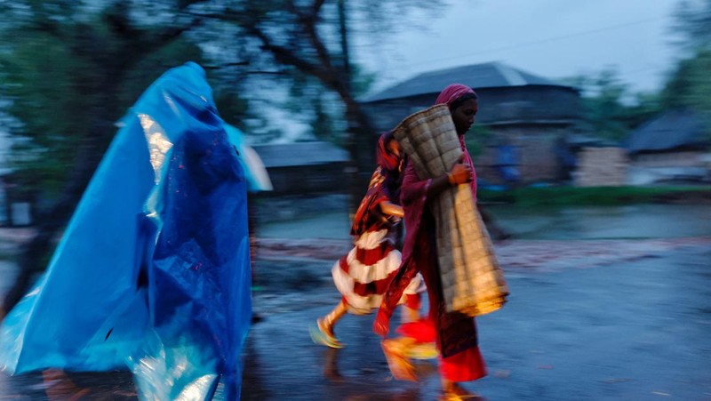 Seorang pria menyelamatkan gerobak dan material lainnya saat air mengalir ke pantai Kuakata di pesisir Teluk Benggala akibat mendekatnya Topan Remal di Barisal, Bangladesh, Minggu, 26 Mei 2024. (AP Photo/Abdul Goni)