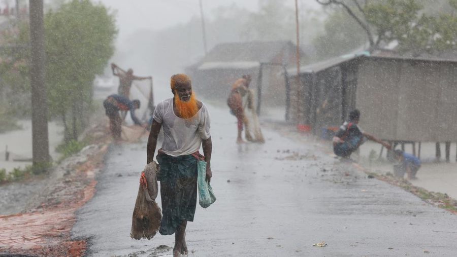 Seorang pria menyelamatkan gerobak dan material lainnya saat air mengalir ke pantai Kuakata di pesisir Teluk Benggala akibat mendekatnya Topan Remal di Barisal, Bangladesh, Minggu, 26 Mei 2024. (AP Photo/Abdul Goni)