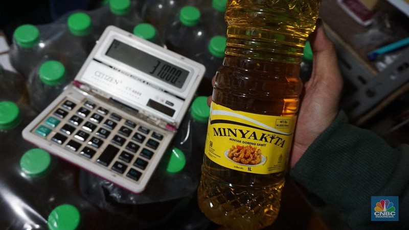 Sejumlah pedagang menunjukkan kemasan botol MinyakKita ukuran dua liter di Kawasan Pasar Santa, Jakarta Selatan, Selasa, (28/5). (CNBC Indonesia/Muhammad Sabki)