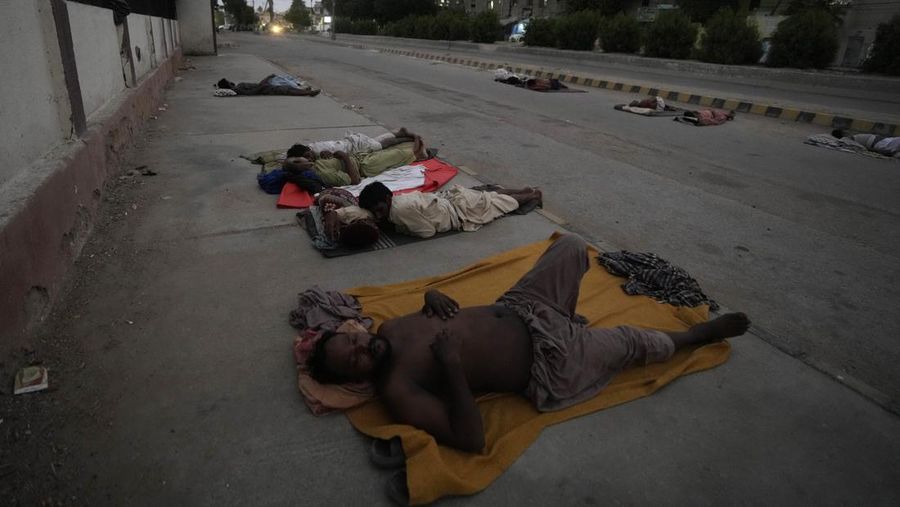 Para buruh tidur di pinggir jalan pada pagi hari musim panas yang terik di Karachi, Pakistan, Rabu (29/5/2024). (AP Photo/Fareed Khan)