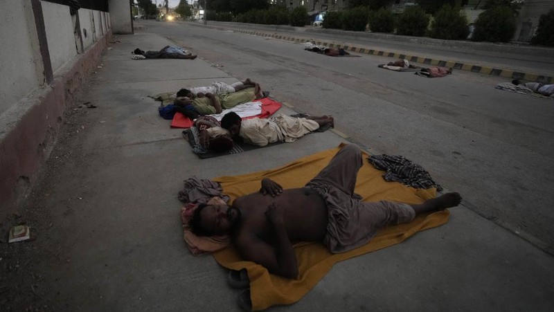 Para buruh tidur di pinggir jalan pada pagi hari musim panas yang terik di Karachi, Pakistan, Rabu (29/5/2024). (AP Photo/Fareed Khan)