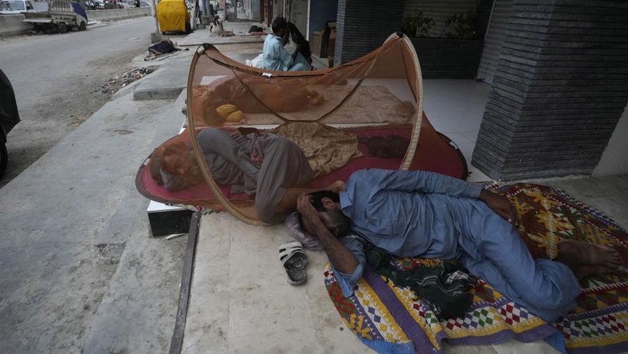 Para buruh tidur di pinggir jalan pada pagi hari musim panas yang terik di Karachi, Pakistan, Rabu (29/5/2024). (AP Photo/Fareed Khan)